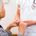 Old woman holding hands with nurse