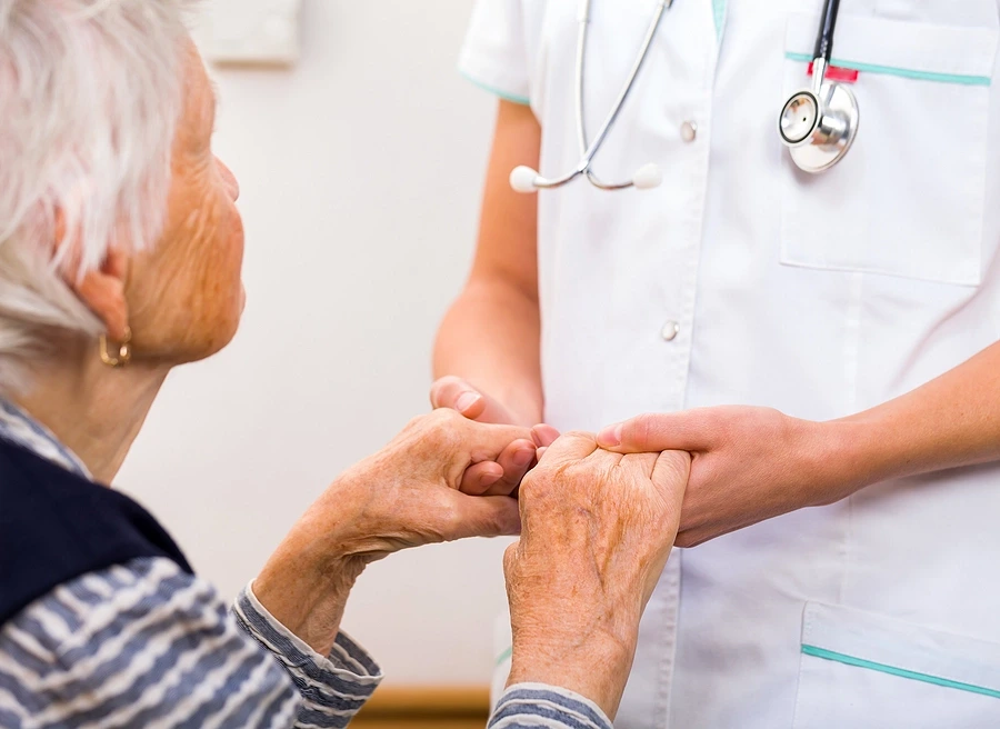 Old woman holding hands with nurse