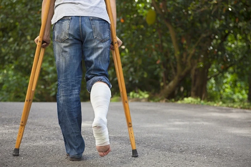 Person in crutches and leg cast walking away