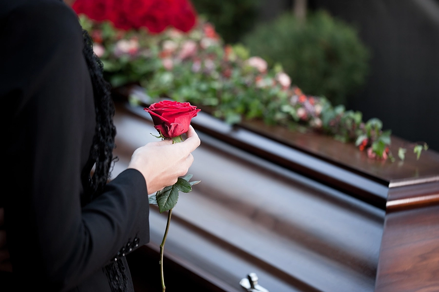 Person-holding-rose-in-front-of-coffin-1